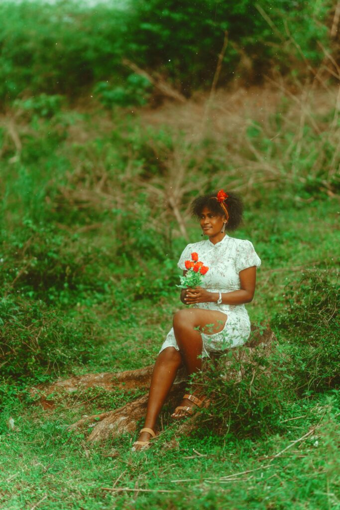 An elegant woman holding vibrant flowers, seated outdoors in Kampala, Uganda.