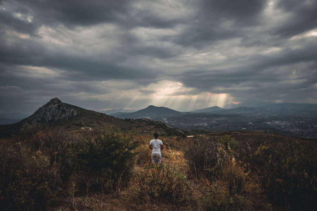 A person gazes at a dramatic cloudy sky over Corinth