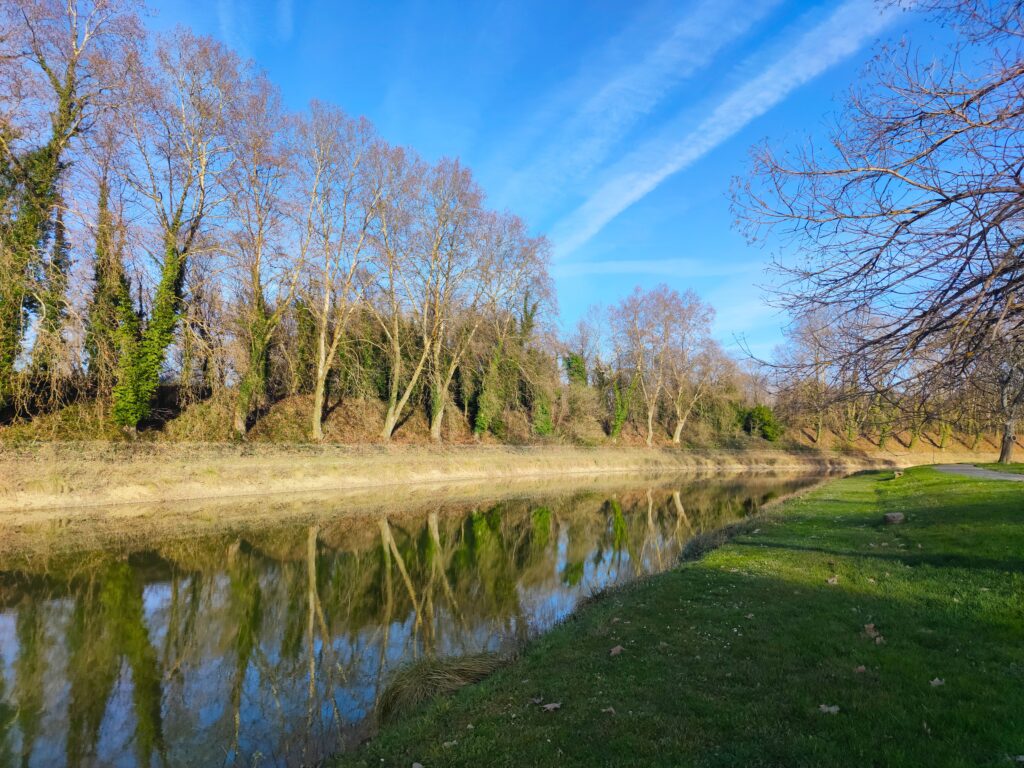 Serene river landscape in Nouvelle-Aquitaine, showcasing reflection of trees and clear blue sky.