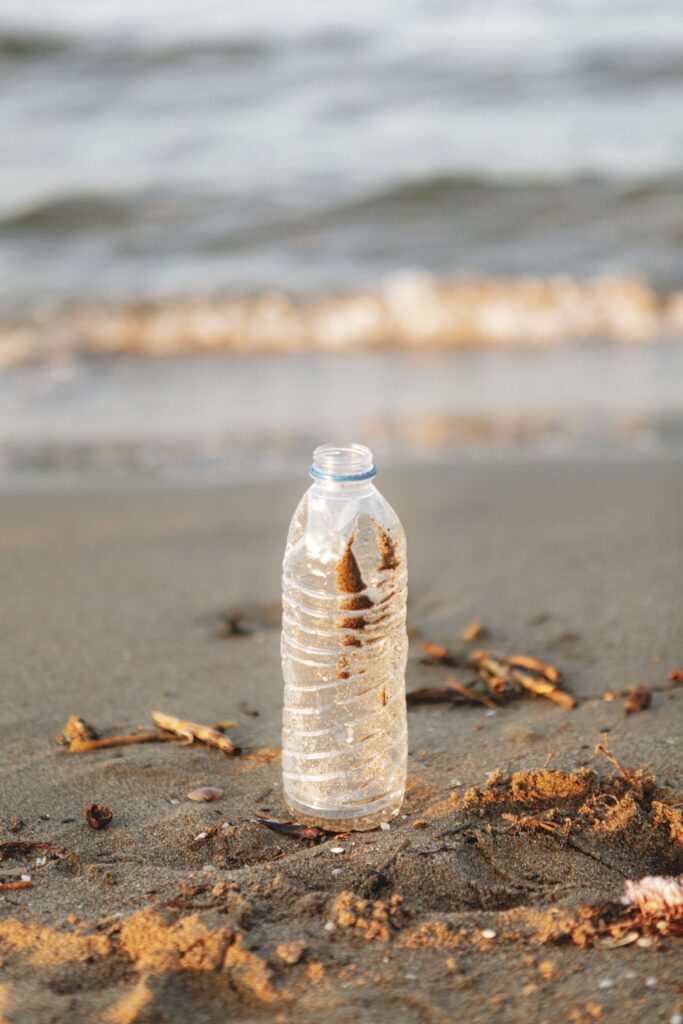 Plastic bottle on sandy shore highlights pollution issue.