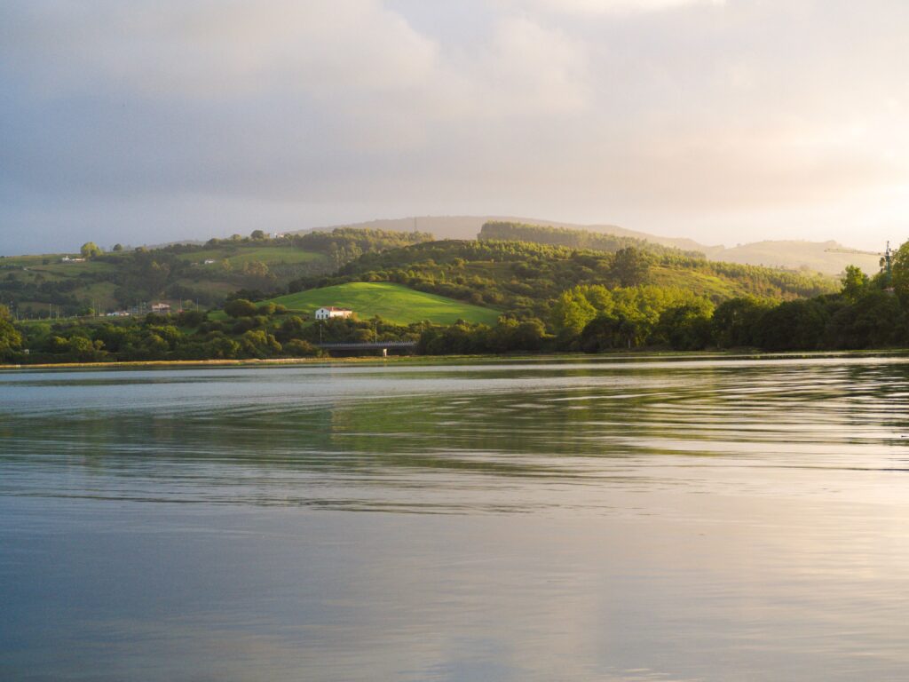 Picturesque landscape of San Vicente de la Barquera with lush hills and calm waters reflecting the serene environment.