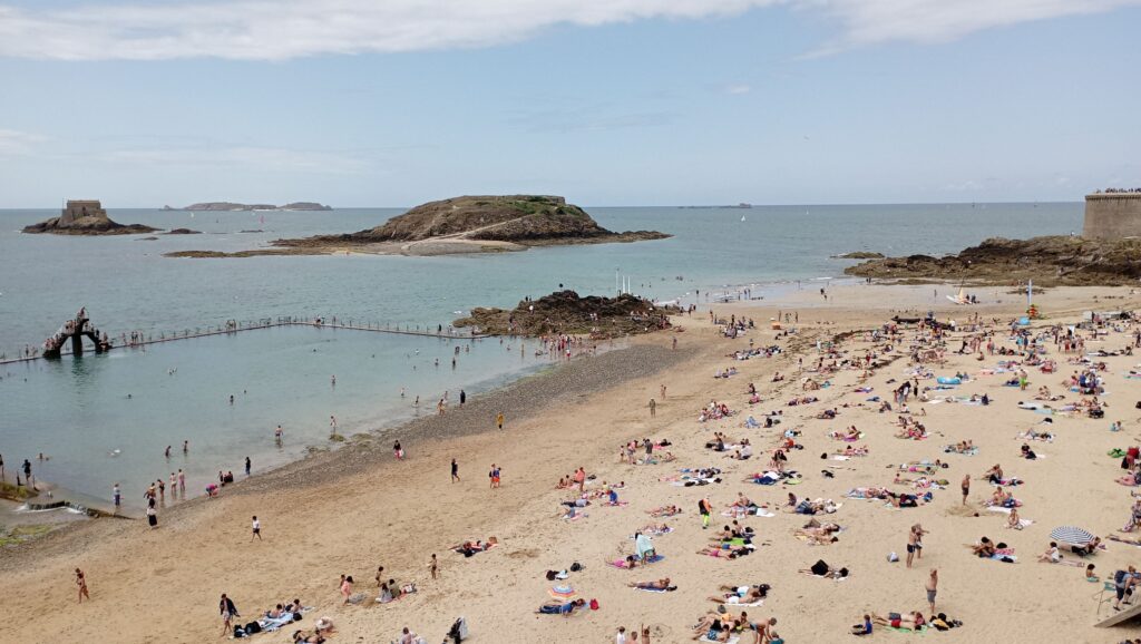 A sunny day at Saint-Malo beach with tourists enjoying the seaside views.