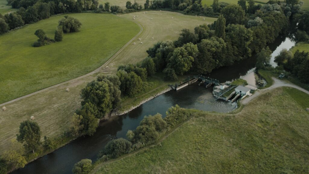 A scenic aerial view of a river lock surrounded by lush greenery in Muttersholtz, France.