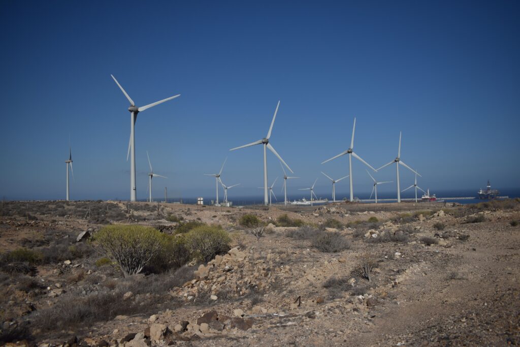 Wind turbines generating renewable energy across a desert landscape with a clear blue sky.