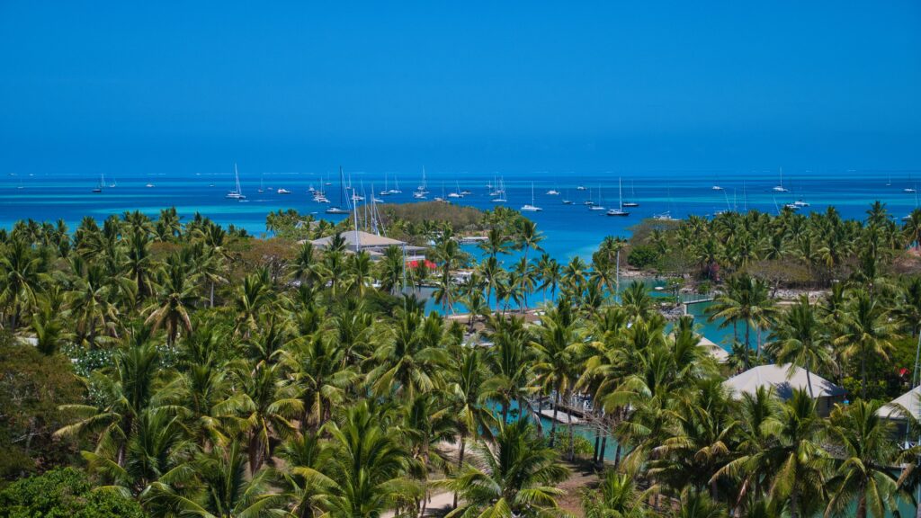 Lush tropical island with palm trees and boats in blue sea, perfect holiday getaway.