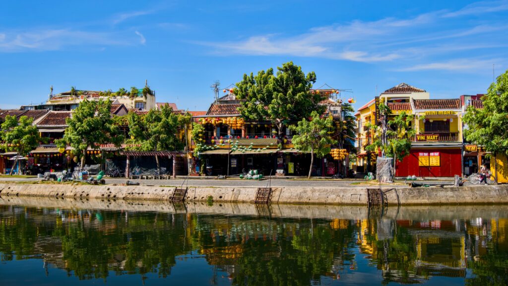 Vibrant riverside scene in Hoi An, showcasing traditional Vietnamese architecture under a clear blue sky.